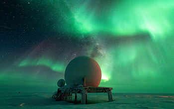 Vibrant green aurora australis and Milky Way over radome